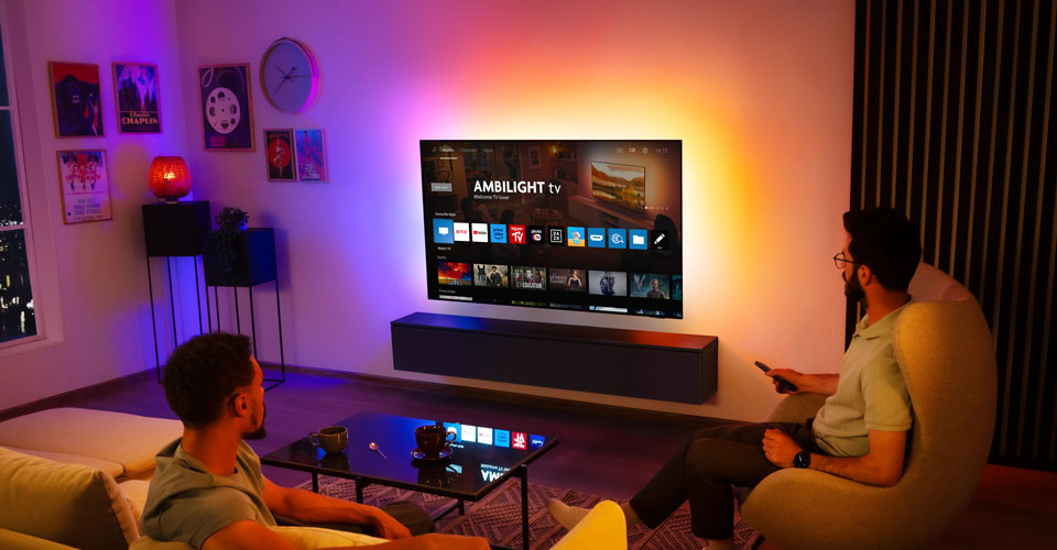 To menn ser p&aring; en veggmontert Ambilight-TV i en stue