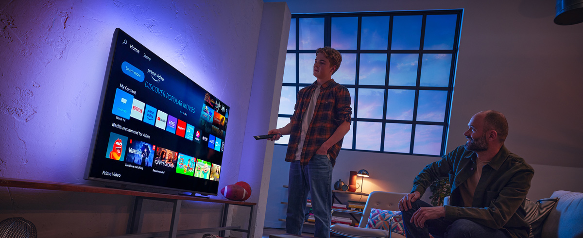 En mann som velger en app p&aring; en smart-TV fra Philips
